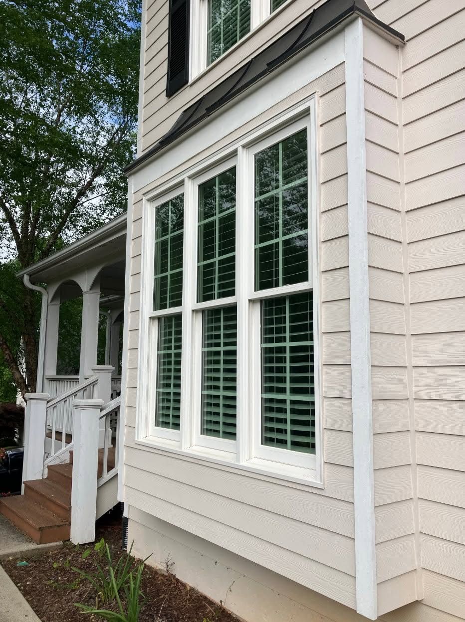 White house siding with three windows and a small porch, viewed from the side