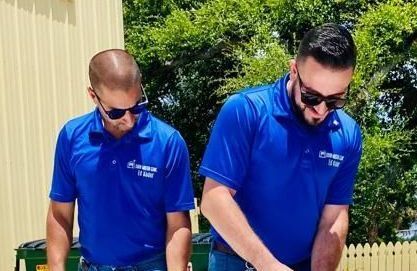 Two men wearing blue shirts and sunglasses are standing next to each other.