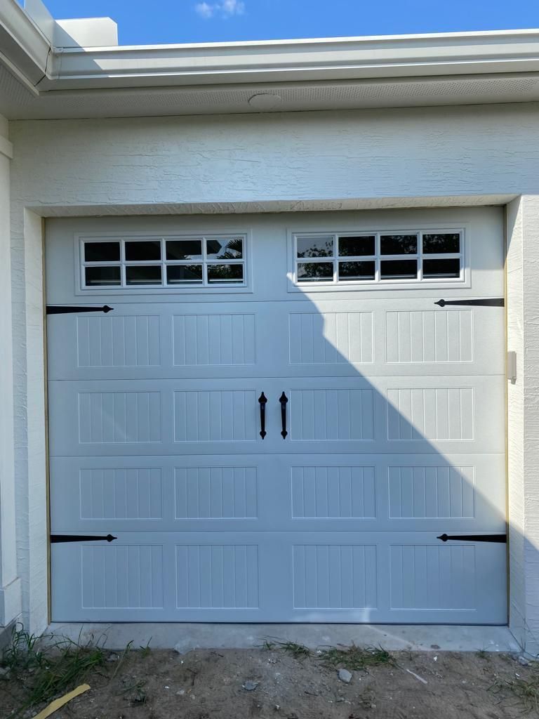 A white garage door with black handles and a window.