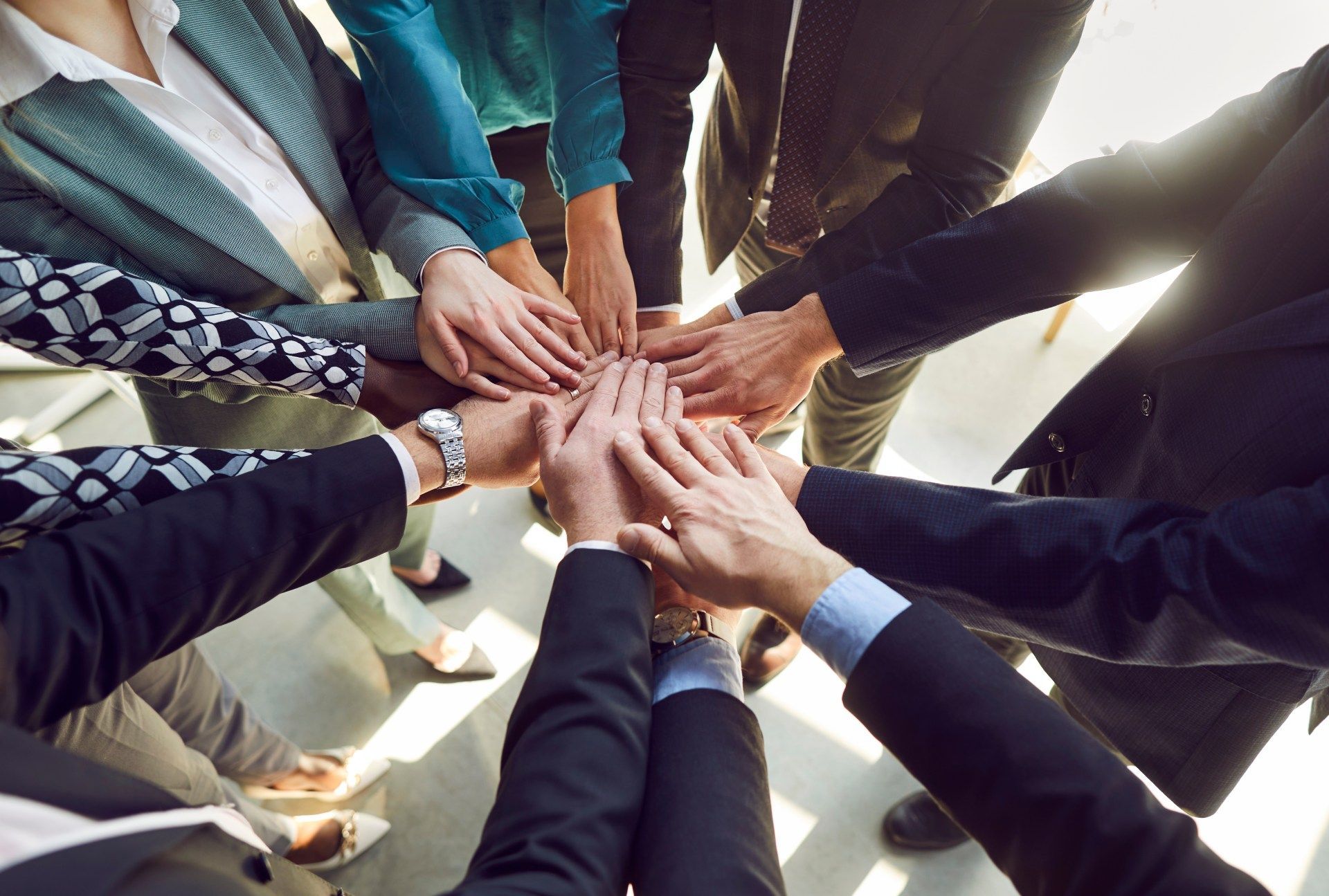 Hands of diverse people in a circle, stacked in unity.