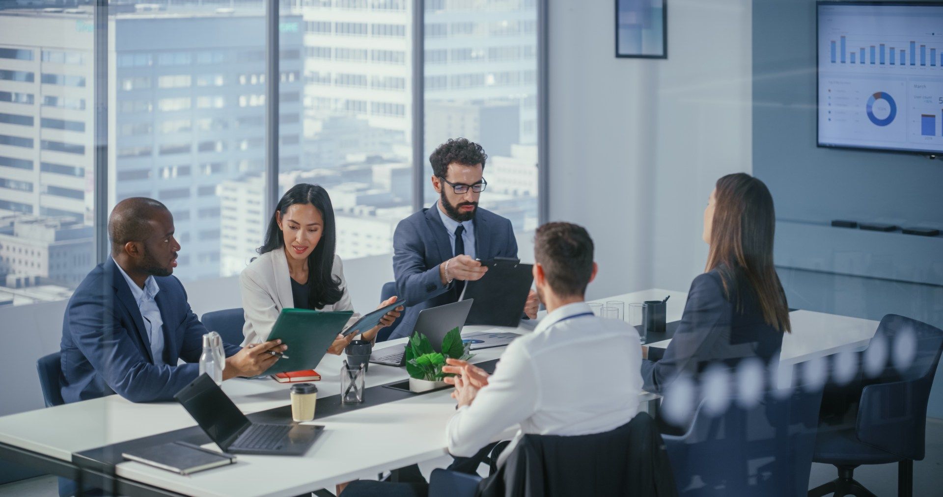 Man and woman looking at laptop, smiling. Man points, woman leans in. Bright office setting.