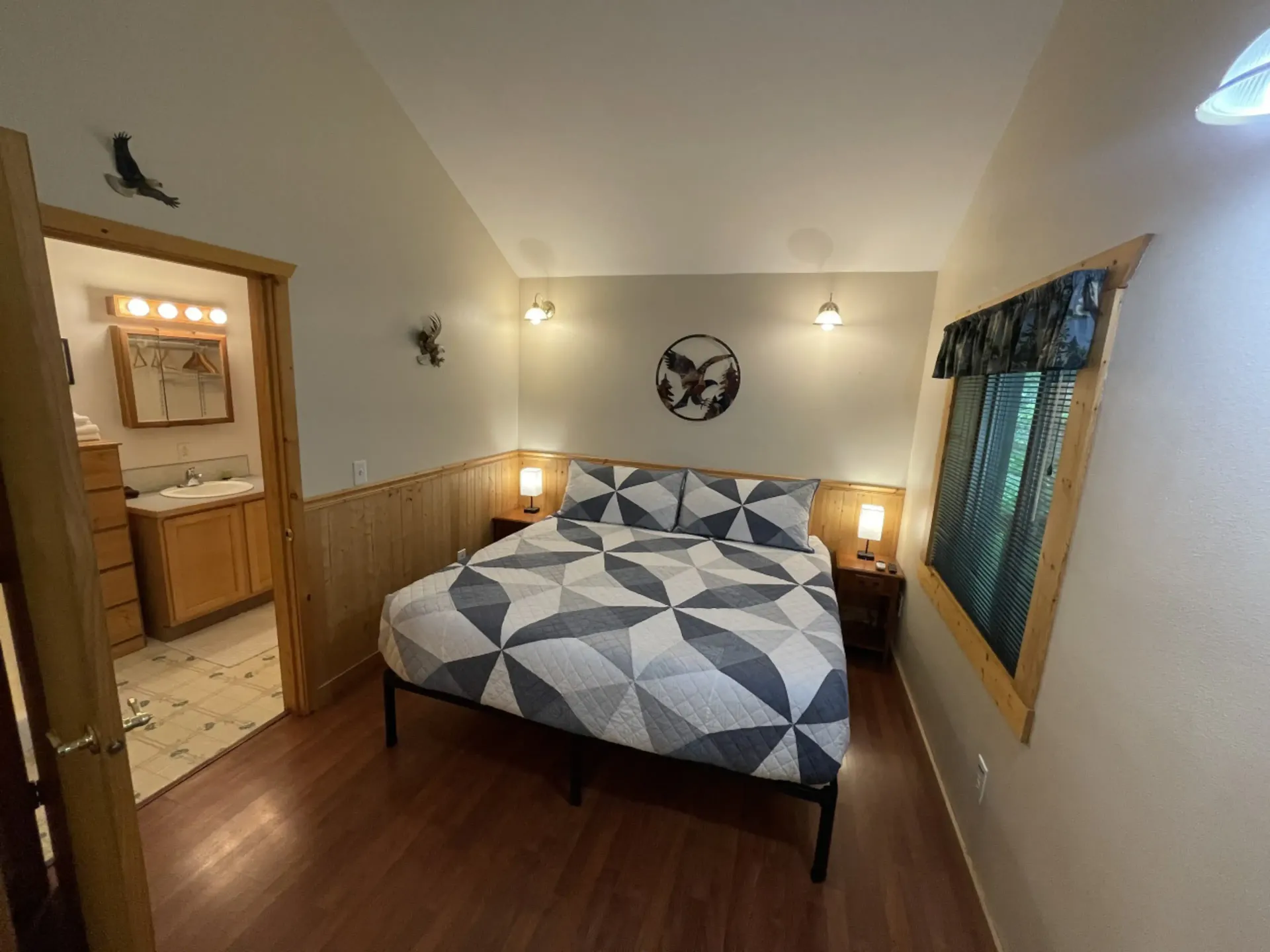 Bedroom with a bed, nightstands, and a door leading to a bathroom. Wall decor includes a bird and metal eagle.