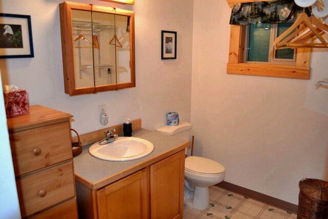 Bathroom with wooden cabinets, a sink, toilet, and a small window.