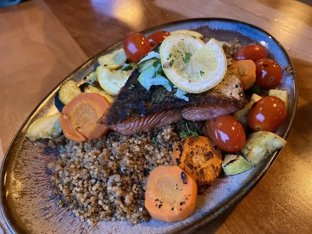 Salmon fillet with vegetables and grains on a plate.