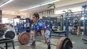 A woman is lifting a barbell in a gym.