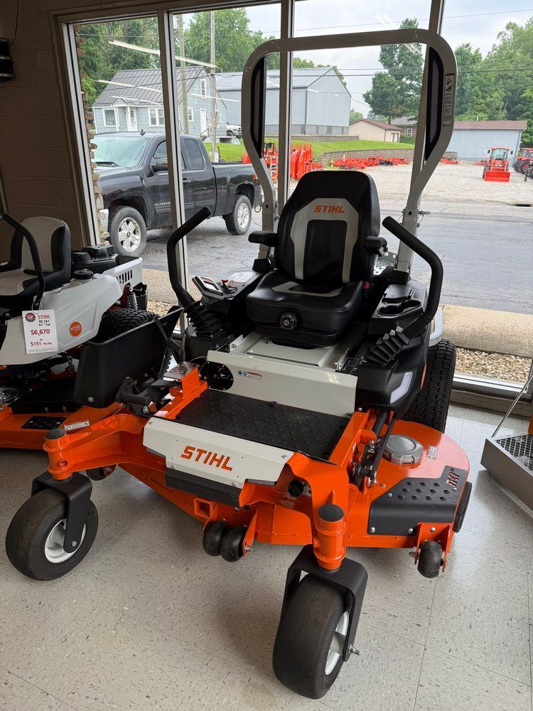 Orange and white STIHL zero-turn lawnmower on display, with black seat and controls.