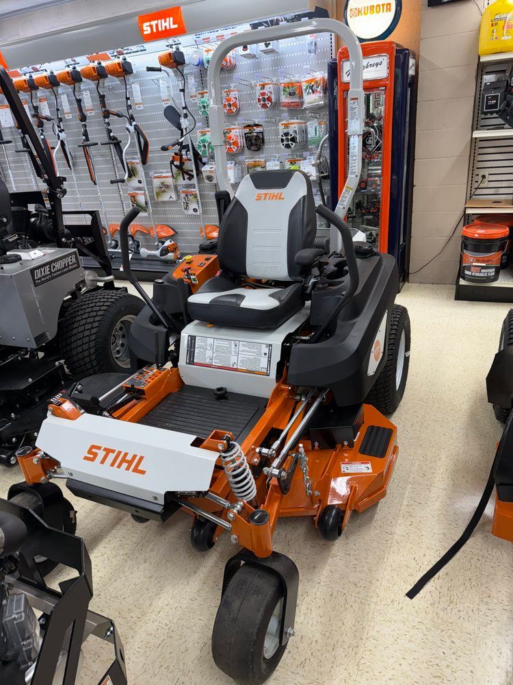 Orange and white Stihl zero-turn mower displayed in a hardware store setting.
