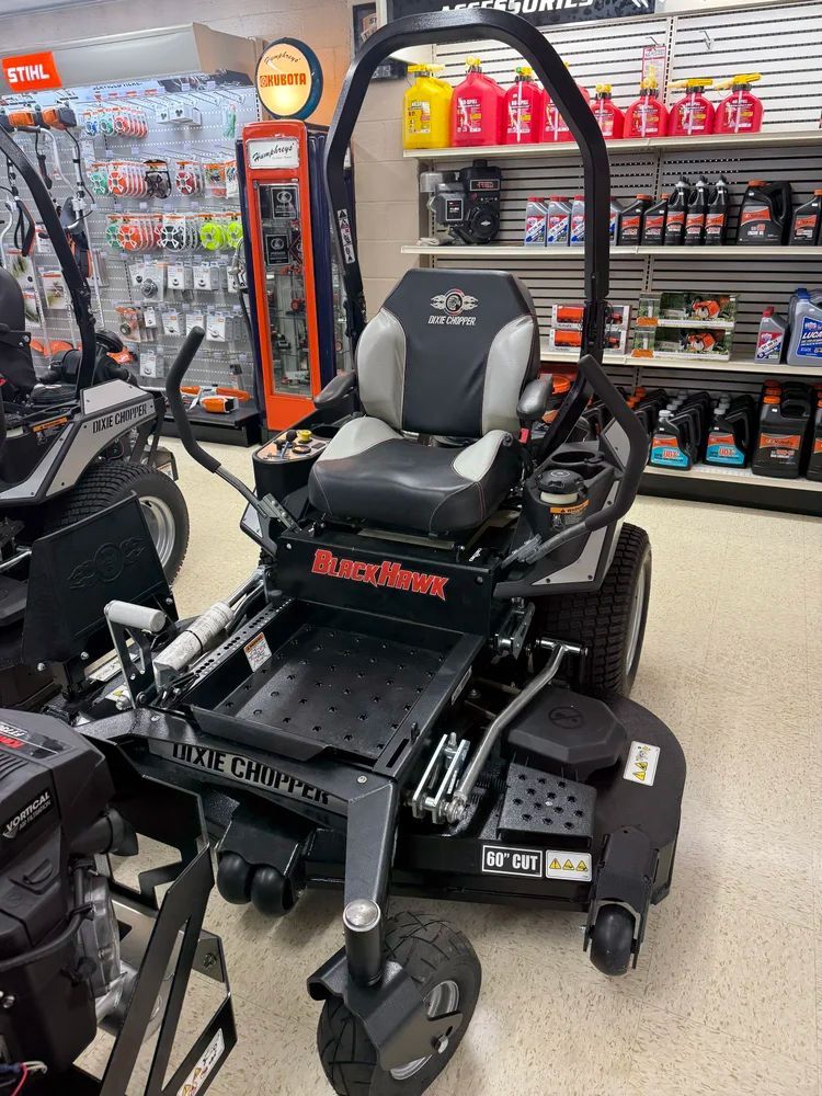 Black and gray zero-turn lawnmower on display inside a store with various products in the background.