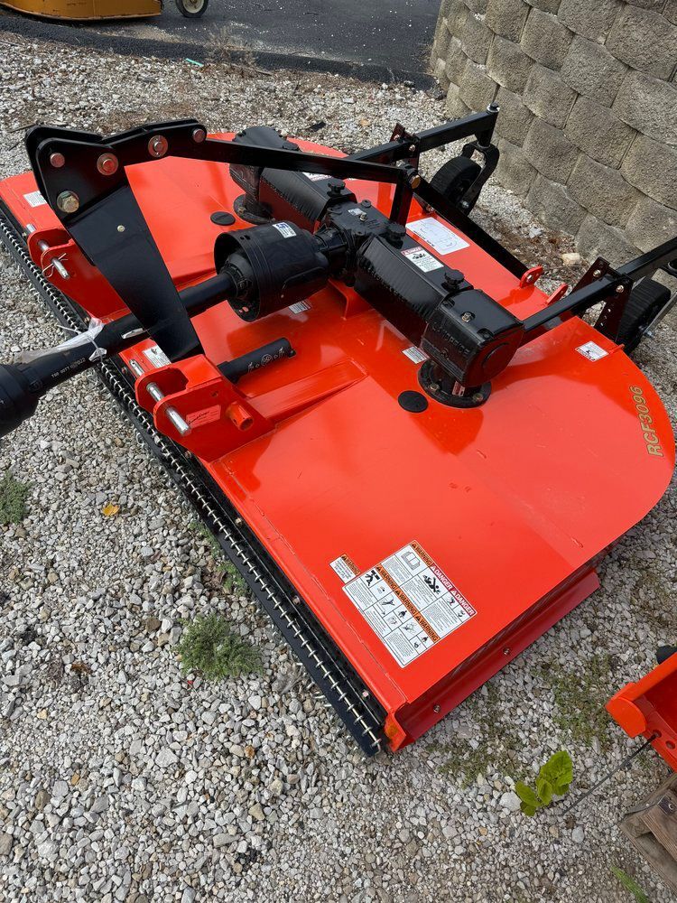 Orange rotary mower on gravel.