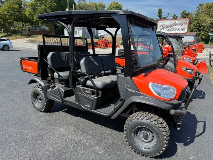 Orange rotary mower with four black wheels and a black hitch.