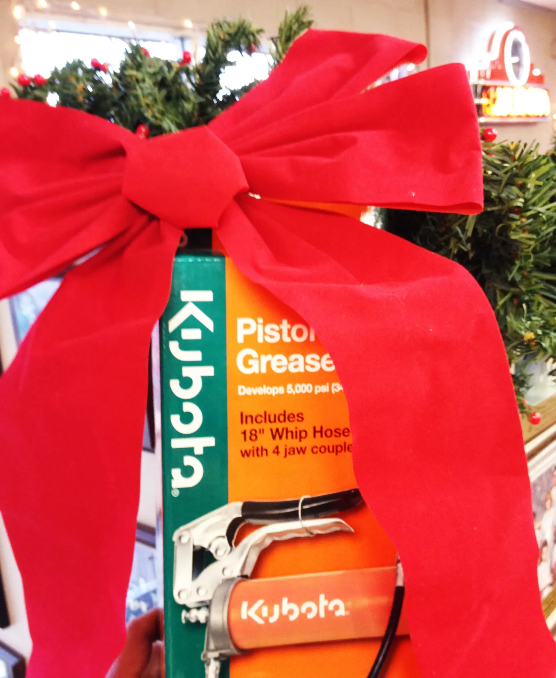 Kubota piston grease gift-wrapped with a red bow. Christmas greenery in the background.