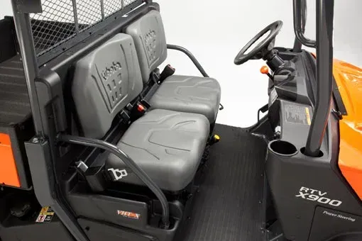 Interior of an orange Kubota RTV-X900 utility vehicle, showing two gray seats with seatbelts, steering wheel