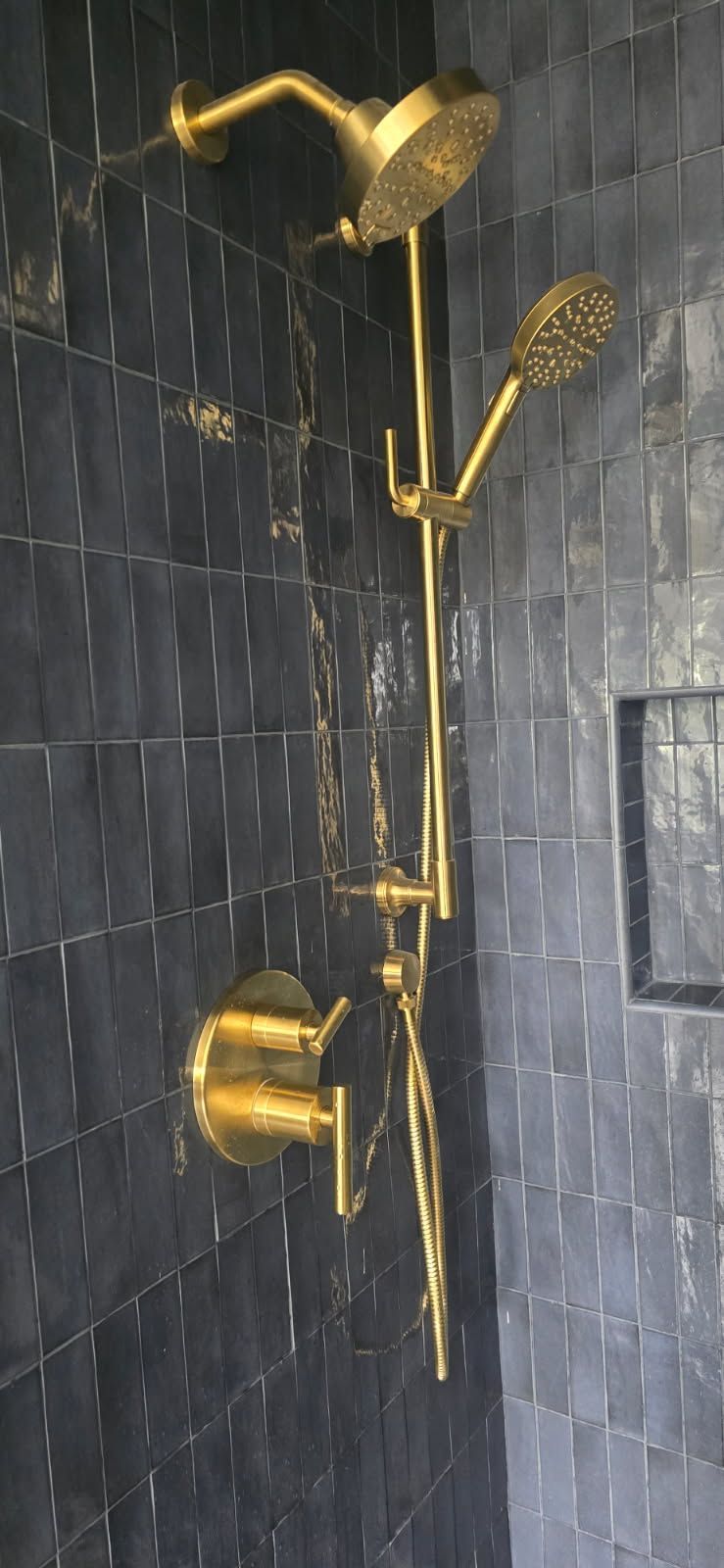 Gold shower set on dark gray tiled bathroom wall