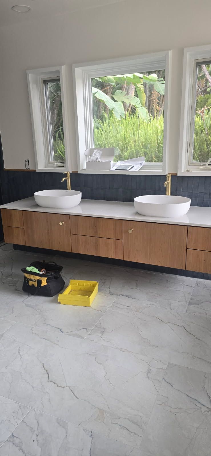 Modern bathroom with double sinks, large windows, and a wooden vanity above a gray tile floor