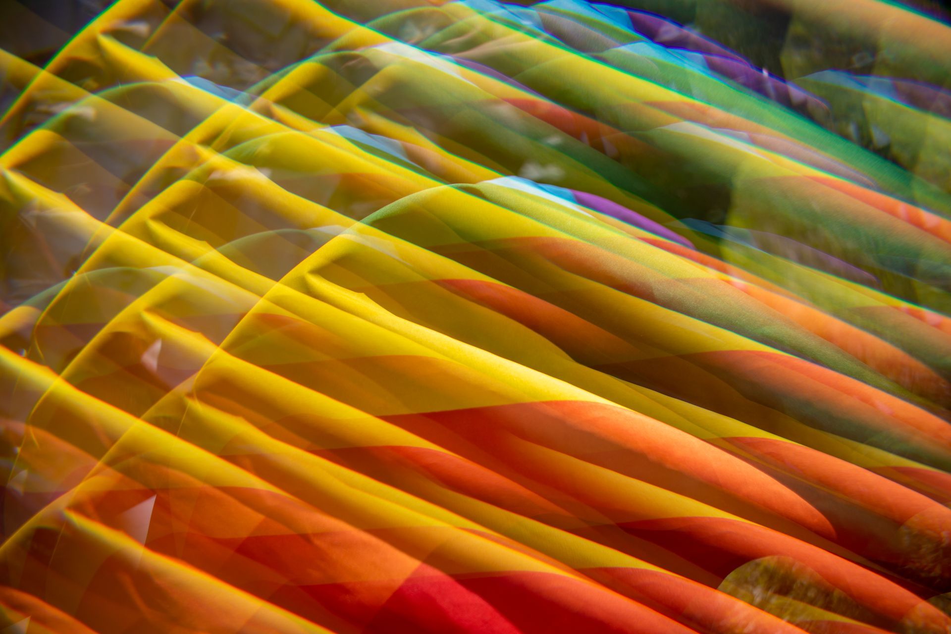 Abstract view of a Pride Flag that is colorful and blurred objects: yellows, oranges, greens, and reds dominate.