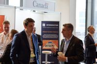 Two business professionals converse at a conference booth with a 