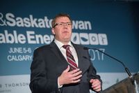 A man in a suit and tie speaks at a podium during a renewable energy conference in Calgary.