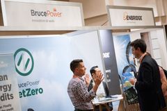 Two people converse at a trade show booth with signage for Bruce Power and Enbridge, focused on their net-zero initiatives.