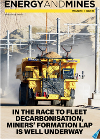 A yellow Komatsu mining truck with a trolley system driving on a dirt road, featured on the cover of Energy and Mines.
