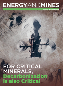 An aerial view of a mine site featuring a cross-shaped processing structure surrounded by piles of light-colored material.