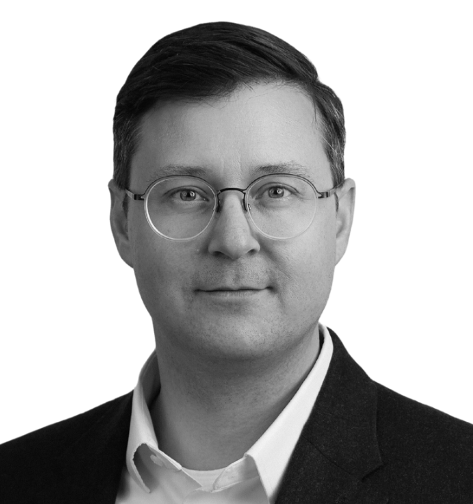 Man in glasses and suit, smiling at the camera.