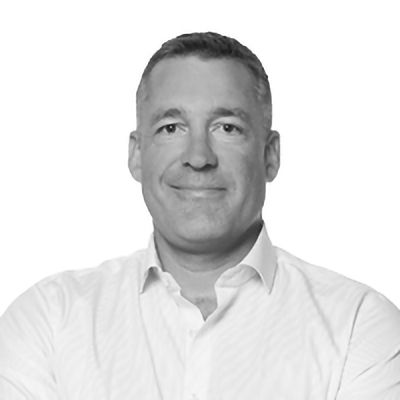 Man in a white button-down shirt smiles, looking at the camera against a white background.