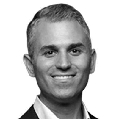 Man in a suit smiles at the camera, black and white portrait.