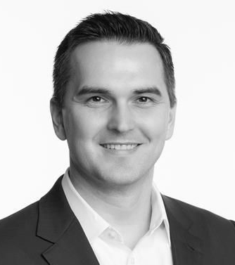 Man with short dark hair, looking directly at the viewer in a black and white photo.