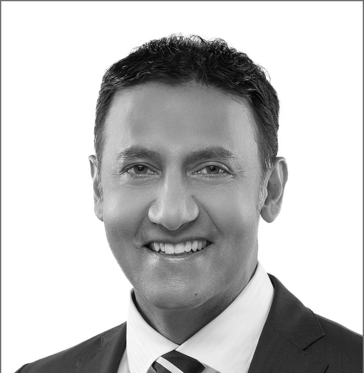 Man in a white button-down shirt smiles, looking at the camera against a white background.