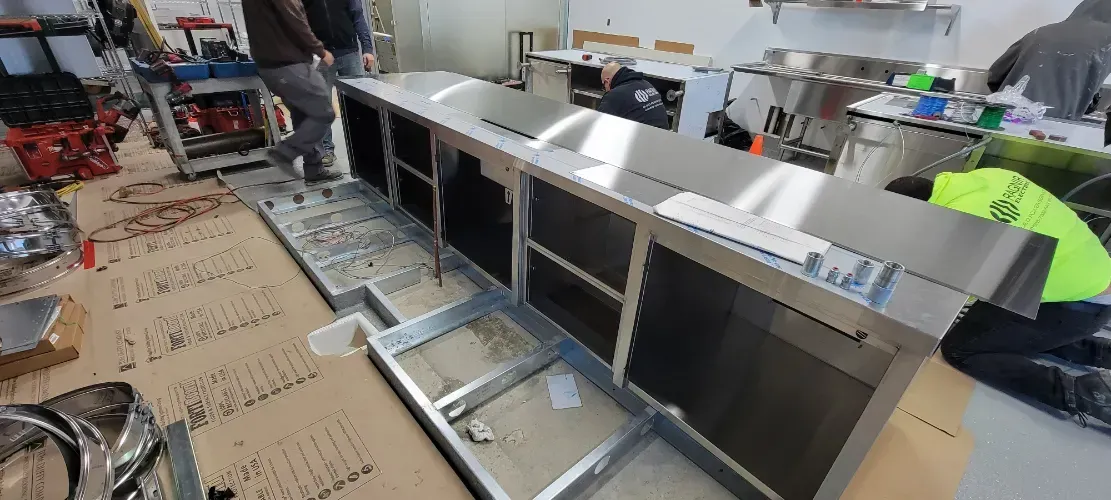 A stainless steel counter top is being built in a kitchen.