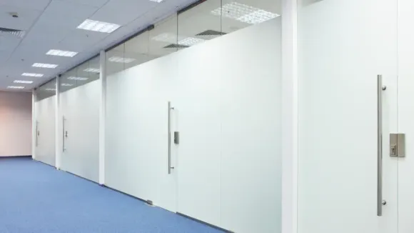A long hallway with white walls and blue carpet in an office building.