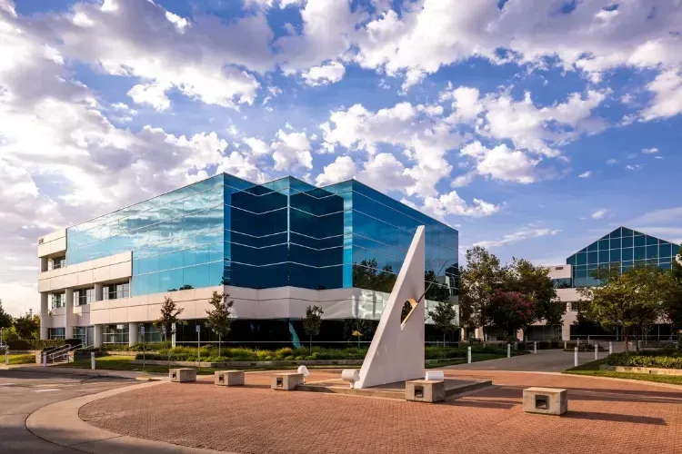 A large glass building with a sculpture in front of it.