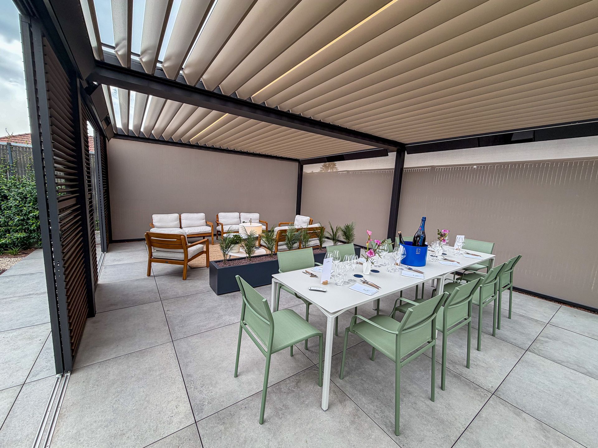 Outdoor dining table with green chairs under a pergola