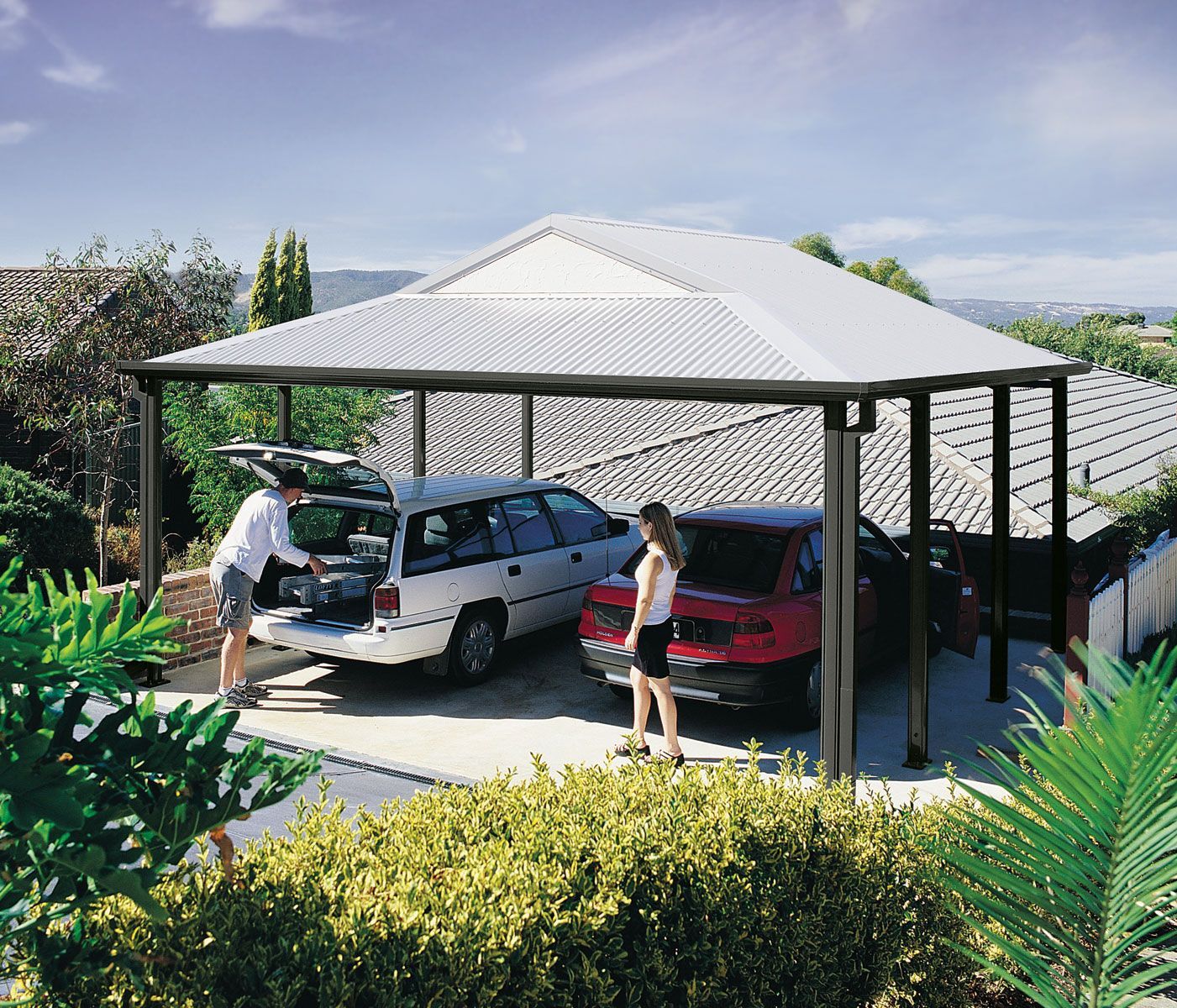 A carport builder installing a metal frame in the backyard of a home.