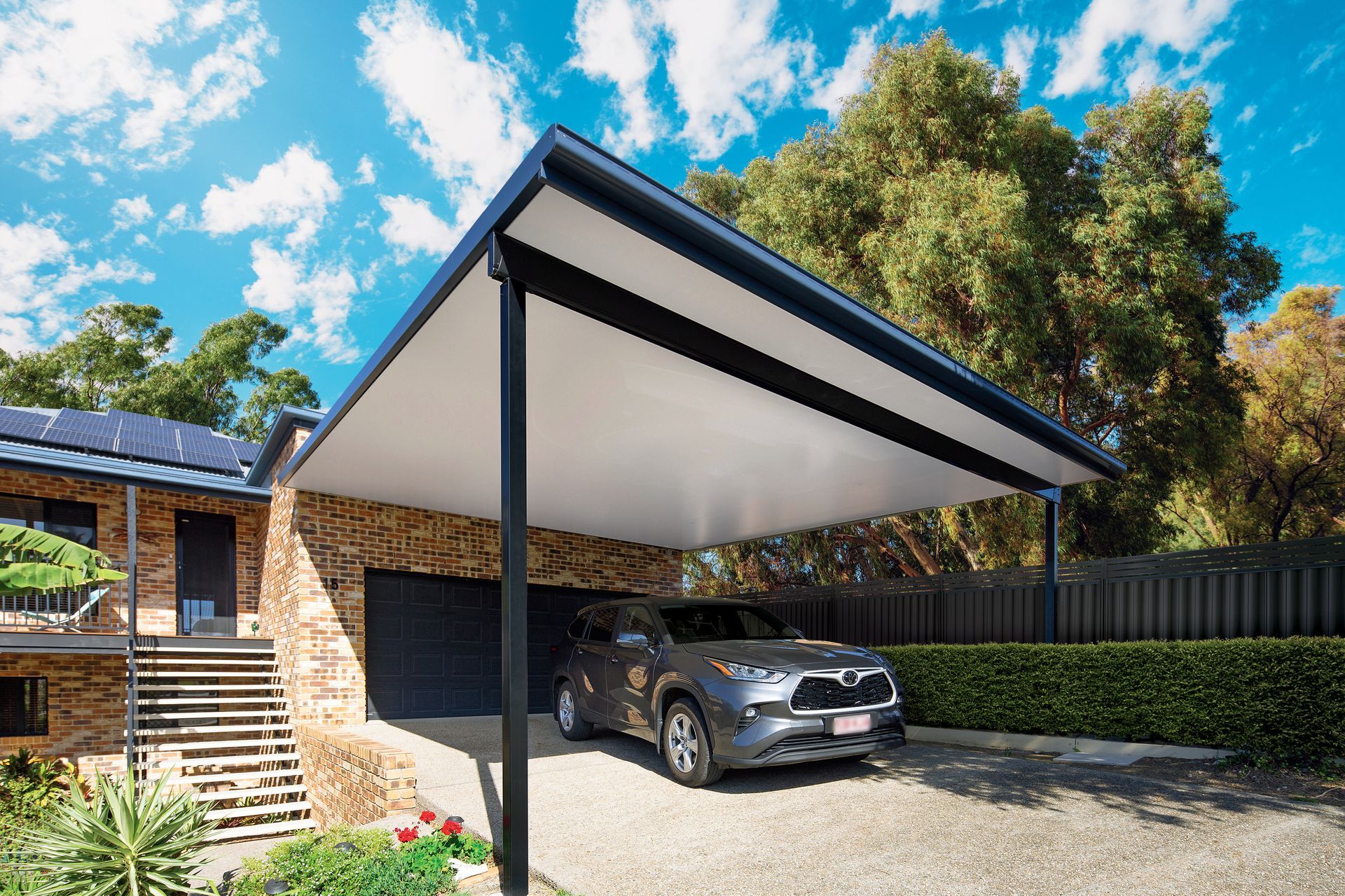 A high-quality carport in a residential area full of green foliage.