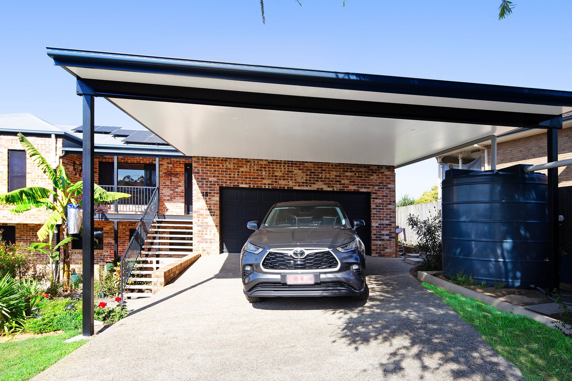 A high-quality carport in a residential area full of green foliage.