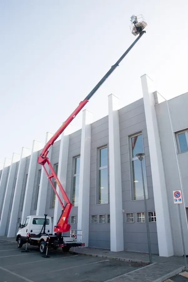 Camion elevatore rosso posizionato in prossimità di un edificio.
