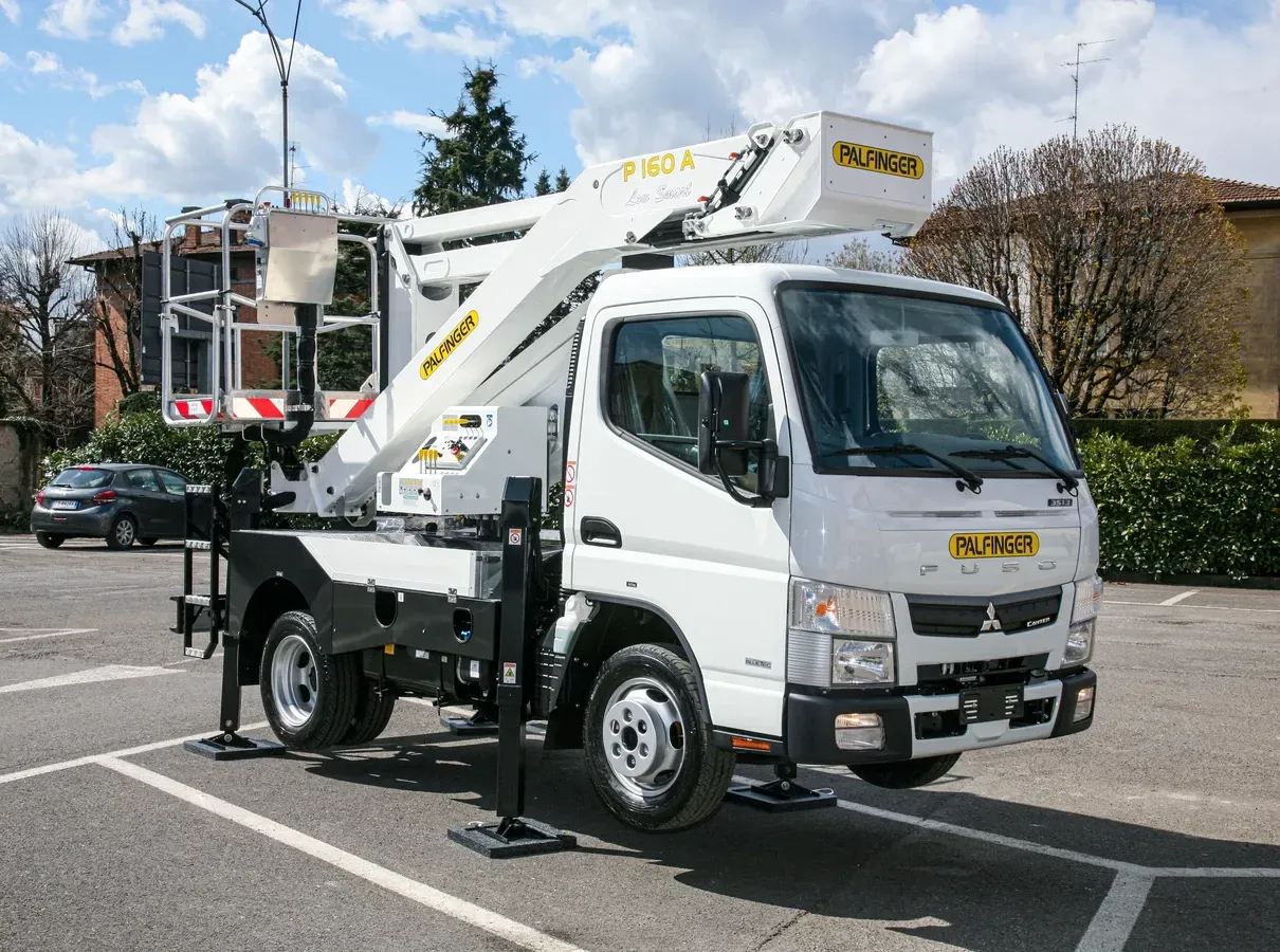 Camion bianco con piattaforma aerea parcheggiato sull'asfalto.