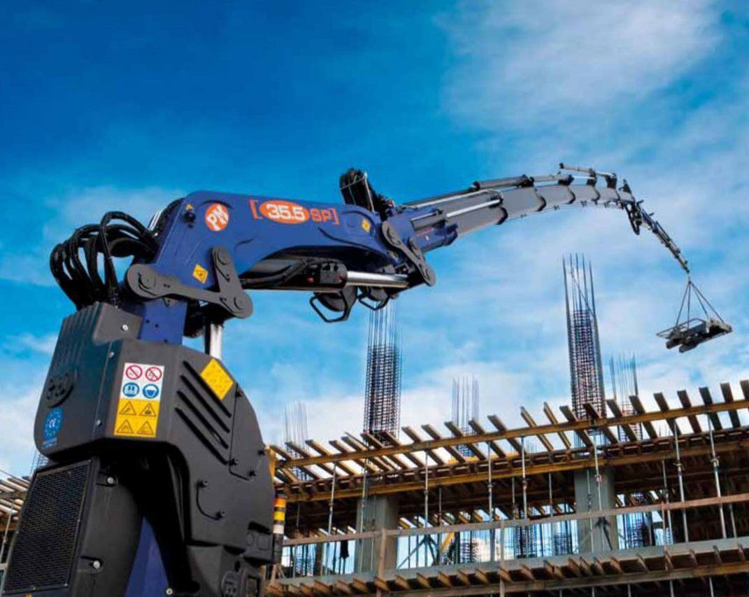 Una gru blu solleva materiali in un cantiere edile.
