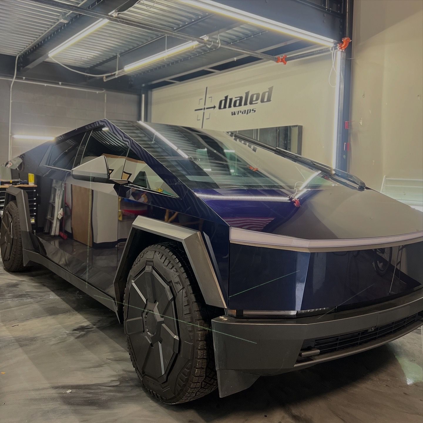 A black car is parked in a garage with a sign that says ' dialed ' on it