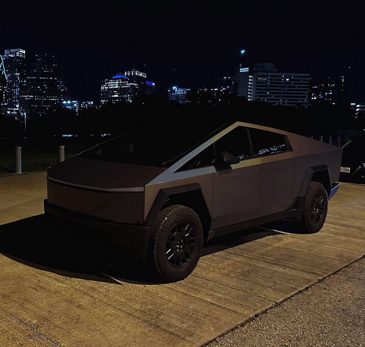 A tesla cybertruck is parked on the side of the road at night.