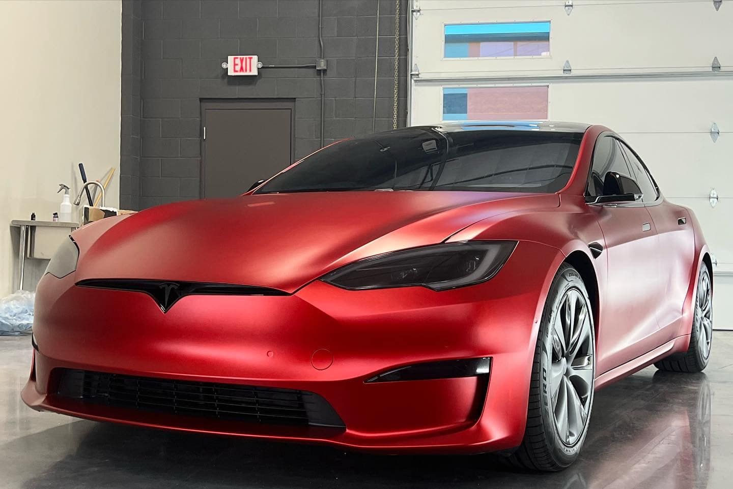 A red tesla model s is parked in a garage.