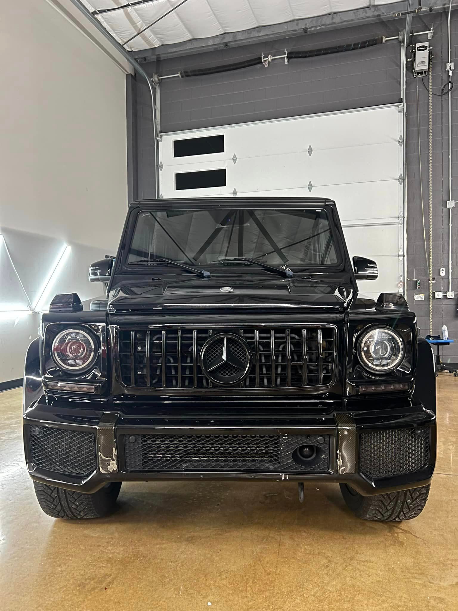 A black mercedes benz g63 is parked in a garage.