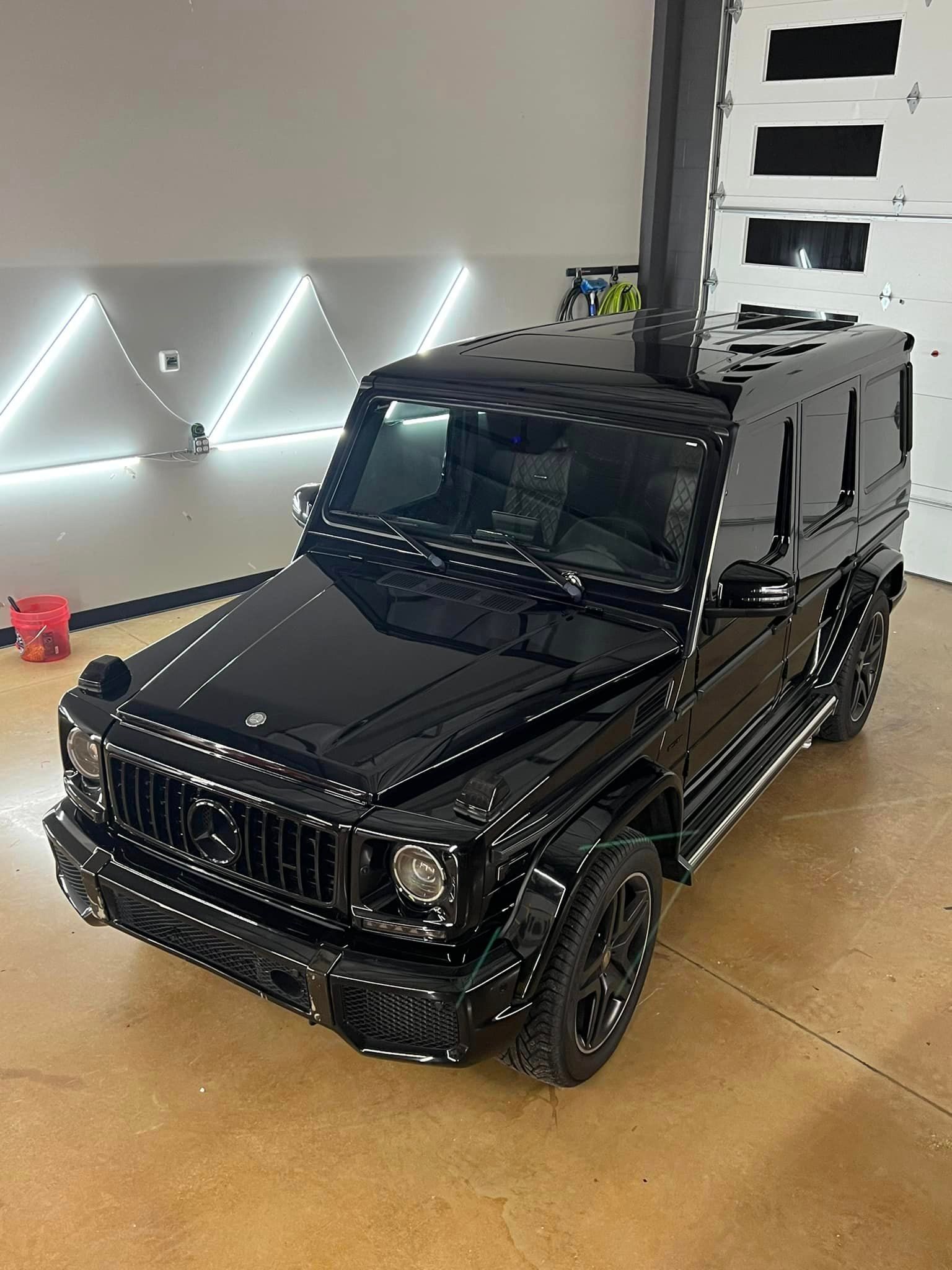 A black mercedes benz g63 is parked in a garage.
