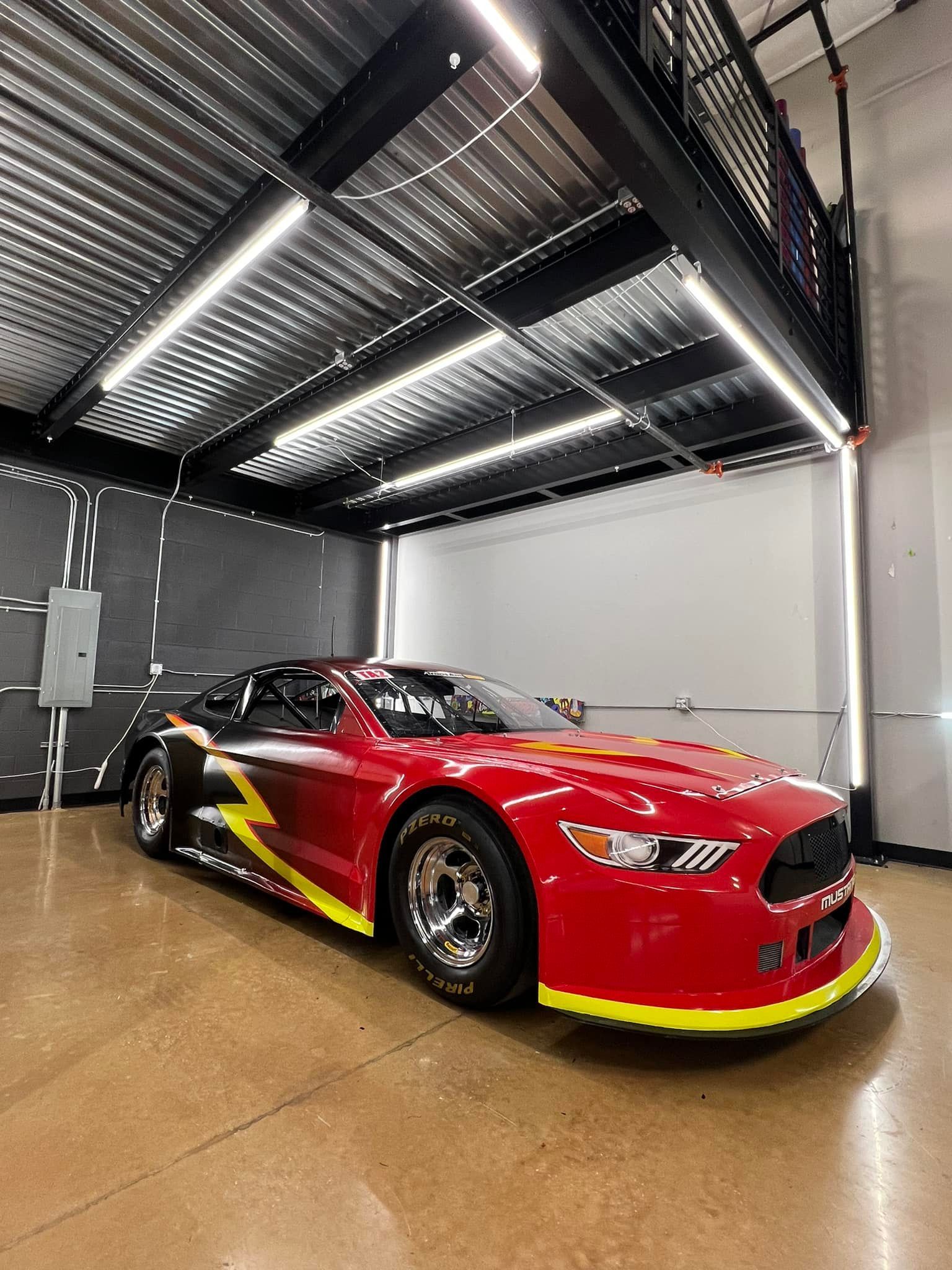 A red race car is parked in a garage.