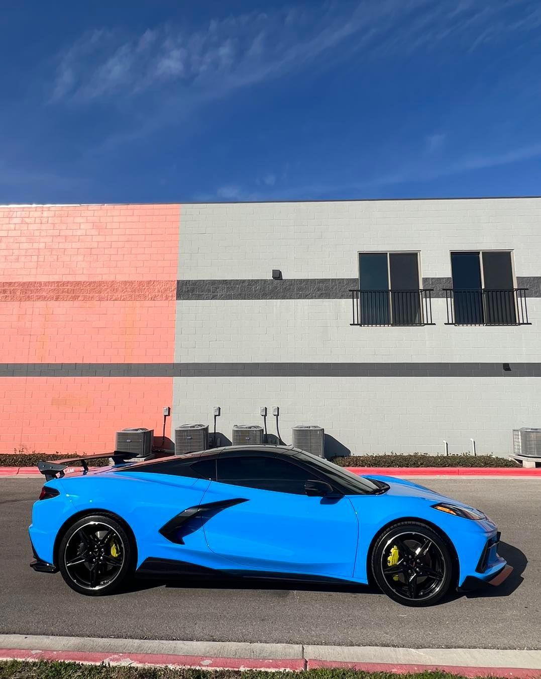 A blue sports car is parked in front of a building.