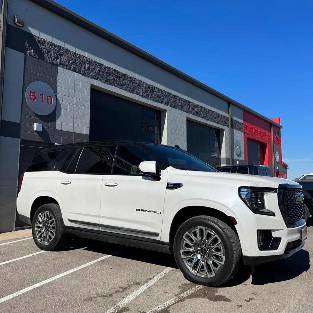 A white suv is parked in front of a building.