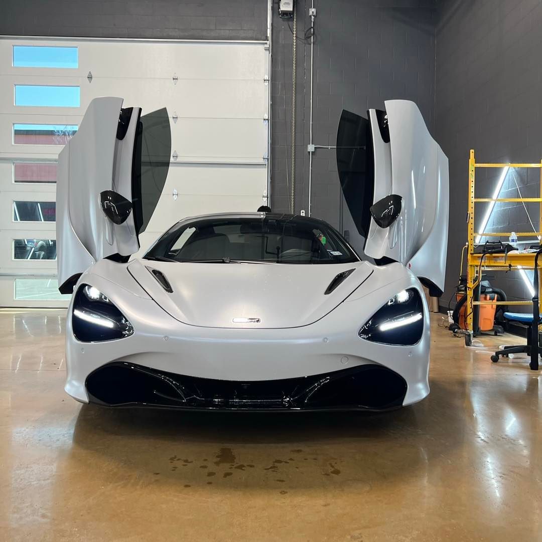 A white sports car is parked in a garage with its doors open