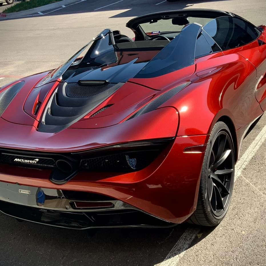 A red sports car is parked in a parking lot