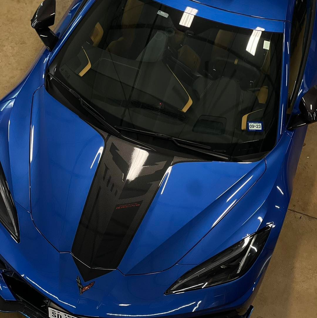 A blue sports car with a black stripe on the hood